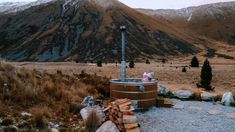 a hot tub sitting on top of a pile of wood next to mountains and trees