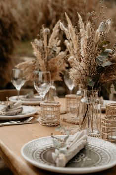 the table is set with place settings and flowers in glass vases on top of plates