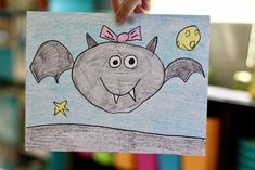 a child's hand holding up a drawing of a bat