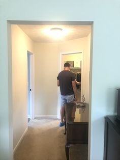 a man standing in front of a mirror next to a tv on a dresser and door