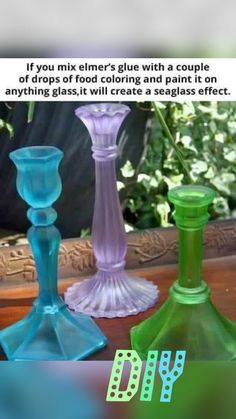 three different colored glass vases sitting next to each other on top of a table