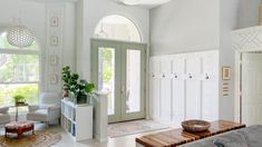 a living room filled with furniture and lots of windows next to a doorway that leads to a patio