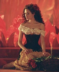 a woman sitting on the floor with flowers in her hair and wearing a corset