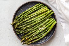 asparagus on a black plate with salt and pepper sprinkled on top