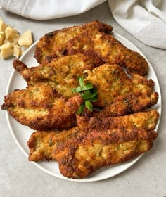 some fried food on a white plate next to garlic and parmesan cheese cubes