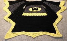 a crocheted batman blanket is laying on the floor with it's hood up