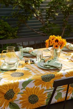 the table is set with sunflowers and glasses on it, along with plates and utensils