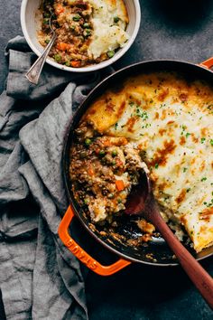 two pans filled with different types of food on top of a cloth covered table