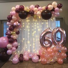 balloons and streamers decorate the entrance to a 60th birthday party with pink, brown, and white balloons