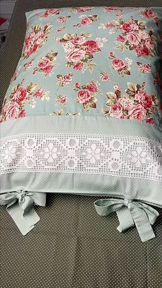 a flowered pillow is sitting on a couch with a lace trim around the edge