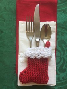 a knitted christmas stocking sits on top of a napkin with silverware