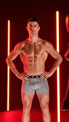 a shirtless man standing in front of red lights with his hands on his hips