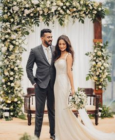 a bride and groom standing in front of an arch decorated with flowers