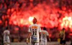 a man with red hair walking on a field in front of a stadium full of people