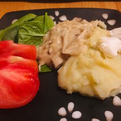 a black plate topped with mashed potatoes and vegetables