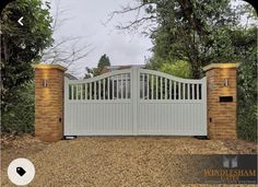 a white gate with brick pillars in front of trees