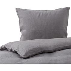 a bed with grey linens and pillows on top of it, against a white background