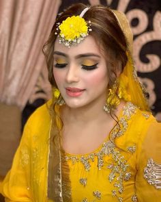 a woman with yellow makeup and flowers in her hair, wearing a yellow veil over her head