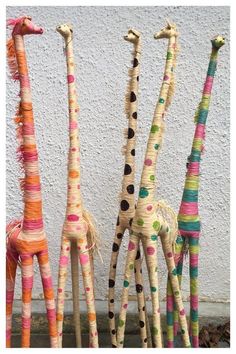 three giraffes made out of straw with different colors and patterns on them