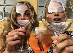 two women holding up wine glasses with their faces painted to look like they are drinking