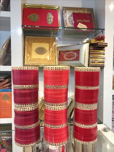 several red and white vases sitting on top of a glass shelf in a store