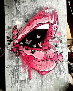 a painting of a pink lips with butterflies on it's tongue and eyes painted on the side of a wall