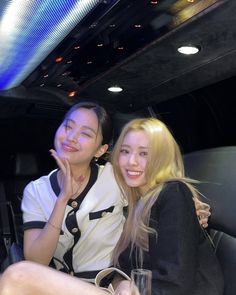 two young women sitting next to each other in a limo car, smiling at the camera