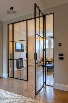 an open glass door leading to a living room with wood flooring and white walls