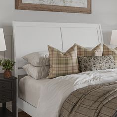 a white bed topped with lots of pillows next to a night stand and nightstands