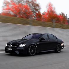 a black mercedes c - class driving down the road