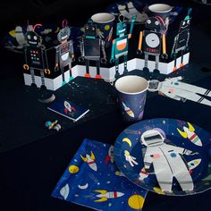 a space themed table setting with napkins, cups and plates on top of it