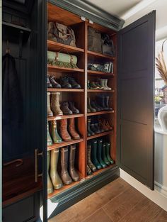 a closet filled with lots of shoes and boots on top of wooden shelves next to a window