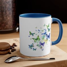 a blue and white coffee mug sitting on top of a wooden table next to a cookie