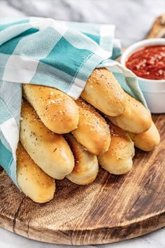 some bread rolls are on a wooden plate with a blue and white towel next to it