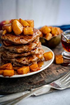 a stack of pancakes on a plate with syrup and butter cubes next to it