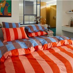 an orange and blue striped bed spread in a room with a painting on the wall