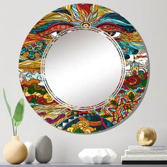 a round mirror sitting on top of a table next to a vase and potted plant