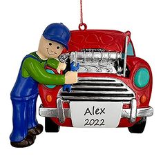 a christmas ornament with a man working on the engine of a red car