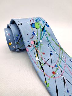 This is a slimline width tie measuring 8cm/3 inches at the blade and 150cm/59 inches in length.  On a base of light blue silk this tie has been hand painted with multicoloured paint splatters in the style of American artist Jackson Pollock.  All of my ties are individually hand painted and no two are ever the same. All dyes used are heat treated and permanent. Hand washing or dry cleaning are recommended. All ties are signed and have my label on the back. All ties come boxed and are wrapped in tissue paper with care instructions. Paint Splatters, Artist Gifts, Jackson Pollock, Wedding Ties, Hand Painted Silk, Tie Accessories, Silk Painting, Blue Silk, Paint Splatter