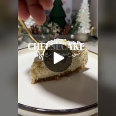 a piece of cheesecake on a white plate with a gold fork and christmas trees in the background