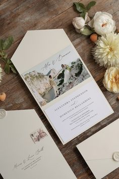 the wedding stationery is laid out on top of the wooden table with flowers and greenery