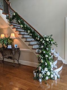 a staircase with flowers and greenery on the bottom, next to a table in front of it