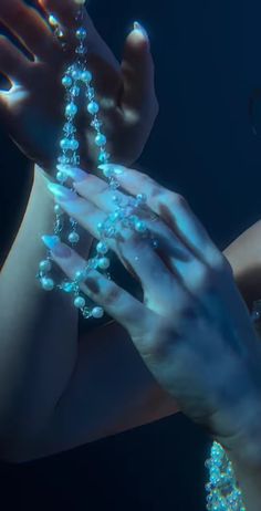 a woman holding beads in her hands with water droplets on it's fingers and the bottom part of her body visible