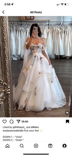 a woman taking a selfie in front of a mirror wearing a white wedding dress