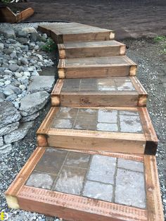 a set of steps made out of wood and stone in the middle of graveled area