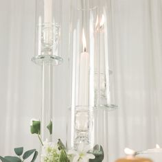 candles and flowers sit in glass vases on a table