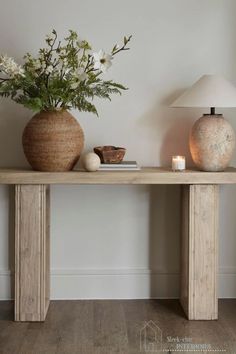 two vases with flowers are sitting on a table next to a lamp and book