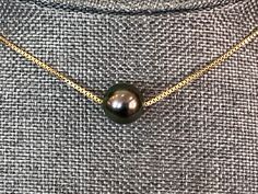 "While a whole Tahitian black pearl necklace or even a triad of matched pearls may be out of reach, one single solitary beautiful Tahitian pearl can be much more affordable and just as stunning. All over Hawaii I saw women rocking a solitaire Tahitian pearl slide on gold box chain like this and I knew I wanted to offer one in my shop. Simple, elegant and beautiful. Wear to work or out to dinner--this necklace knows how to play all day and still party all night. These are all natural, undyed 10mm Formal Black Tahitian Pearl Necklace, Formal Black Tahitian Pearl Necklaces, Engraved Necklace Mothers, Tahitian Black Pearl Necklace, Raven Skull Necklace, Custom Engraved Necklace, Rosary Chain Necklace, Long Stone Necklace, Claw Necklace