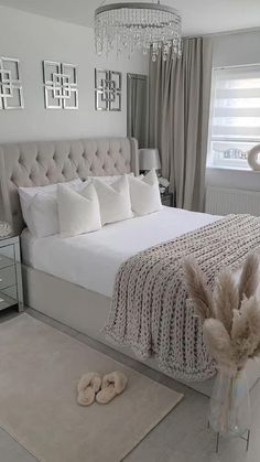 a bedroom with a white bed, chandelier and pillows on the headboard