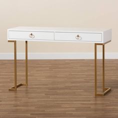 a white and gold desk with two drawers on one side, against a beige wall